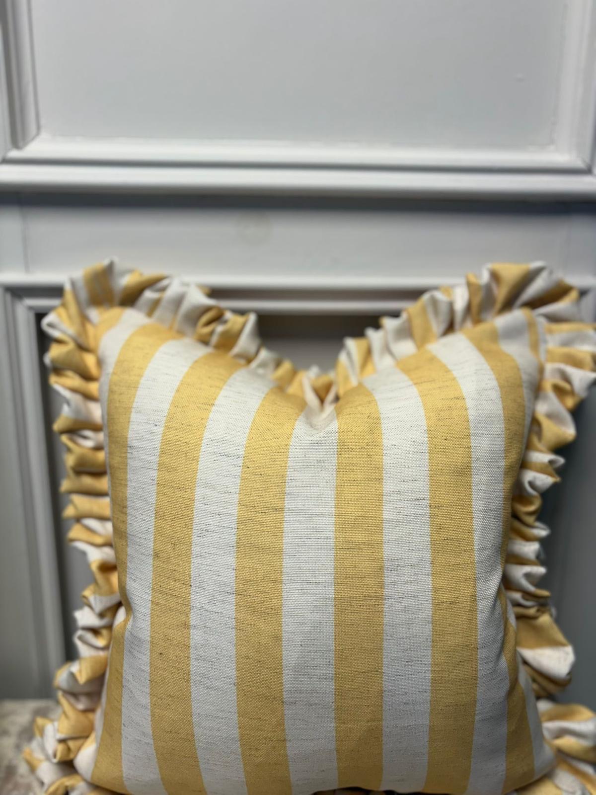 A frilled-edge cushion in buttercup yellow and white stripe fabric