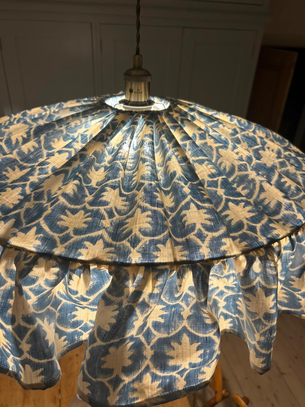 The same powder blue botanical lampshade, glowing warmly when lit